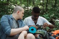 Focused hiker showing backpack to friend