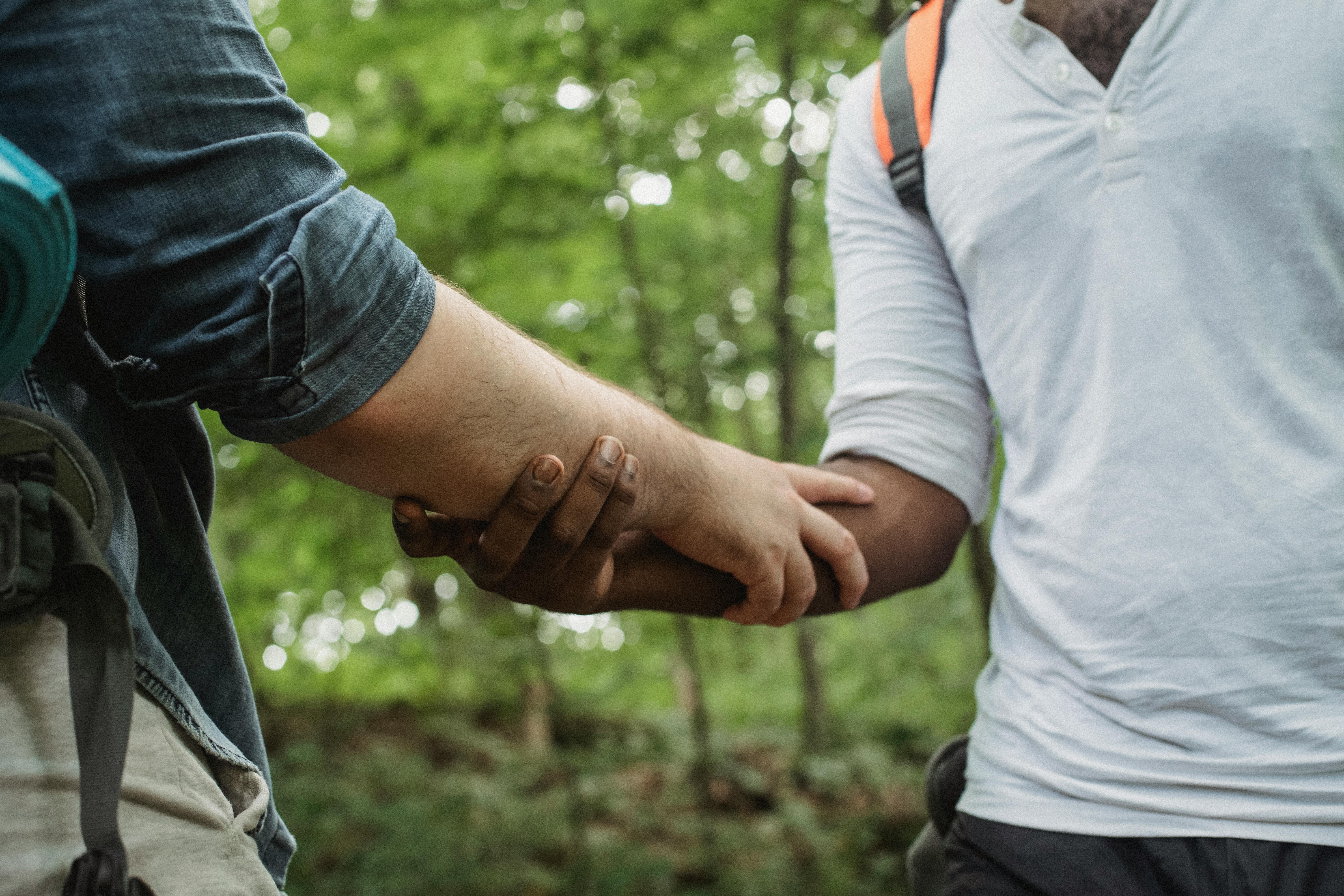 diverse travelers holding arms in forest