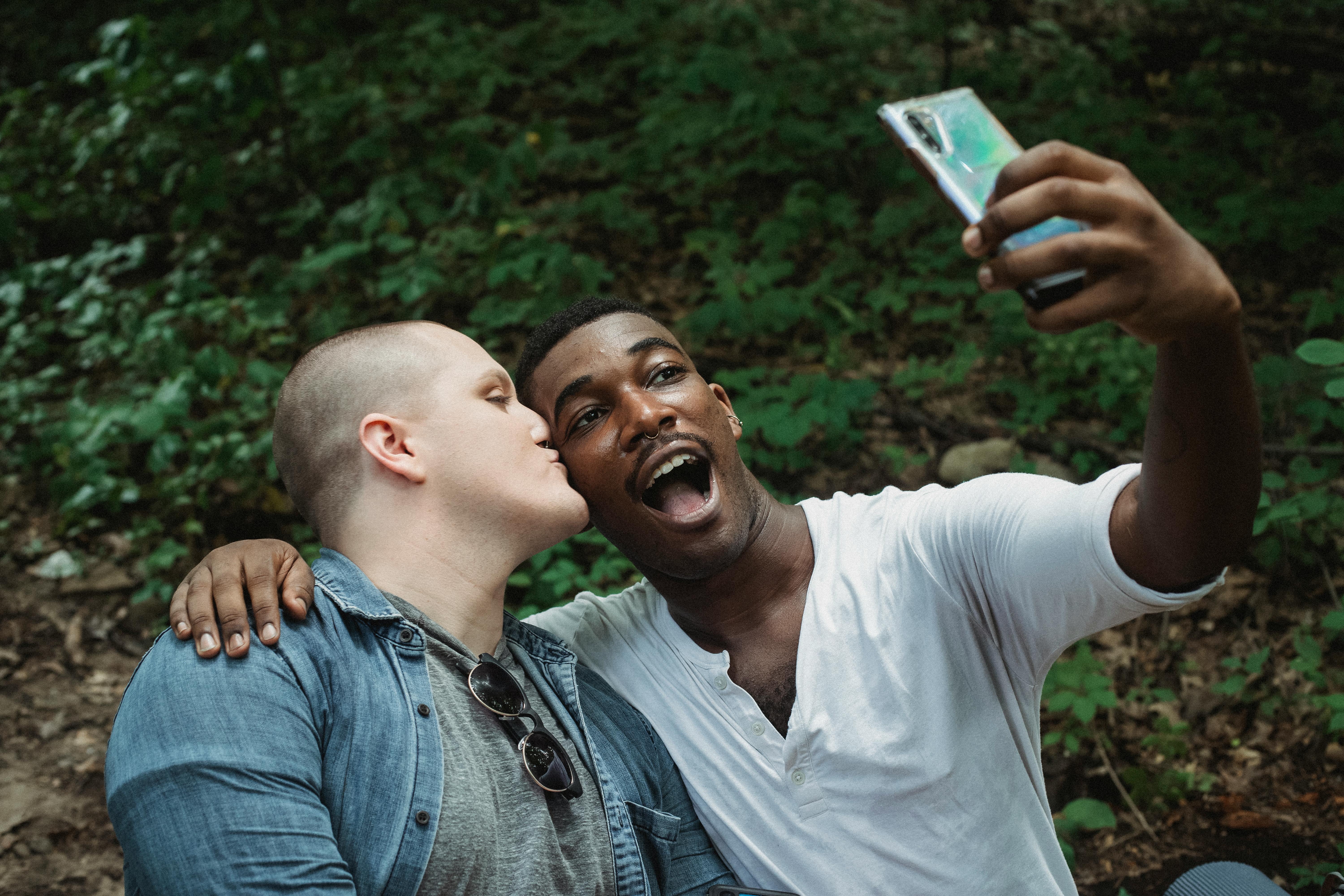 young lgbt couple taking selfie in forest