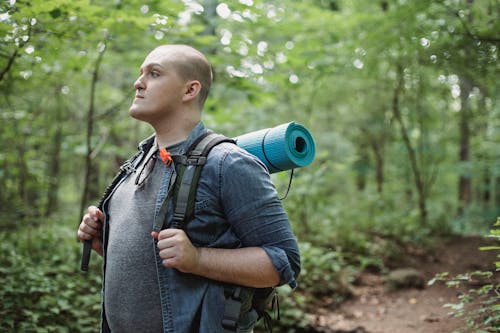 пухлый мужчина турист с походным снаряжением в лесу