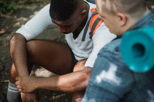 Free From above of disappointed African American male hiker feeling hopeless talking to friend  and looking down Stock Photo
