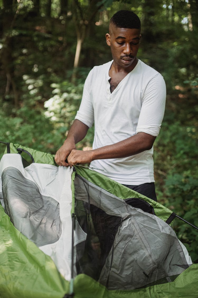 African American Man Putting Camping Tent In Forest