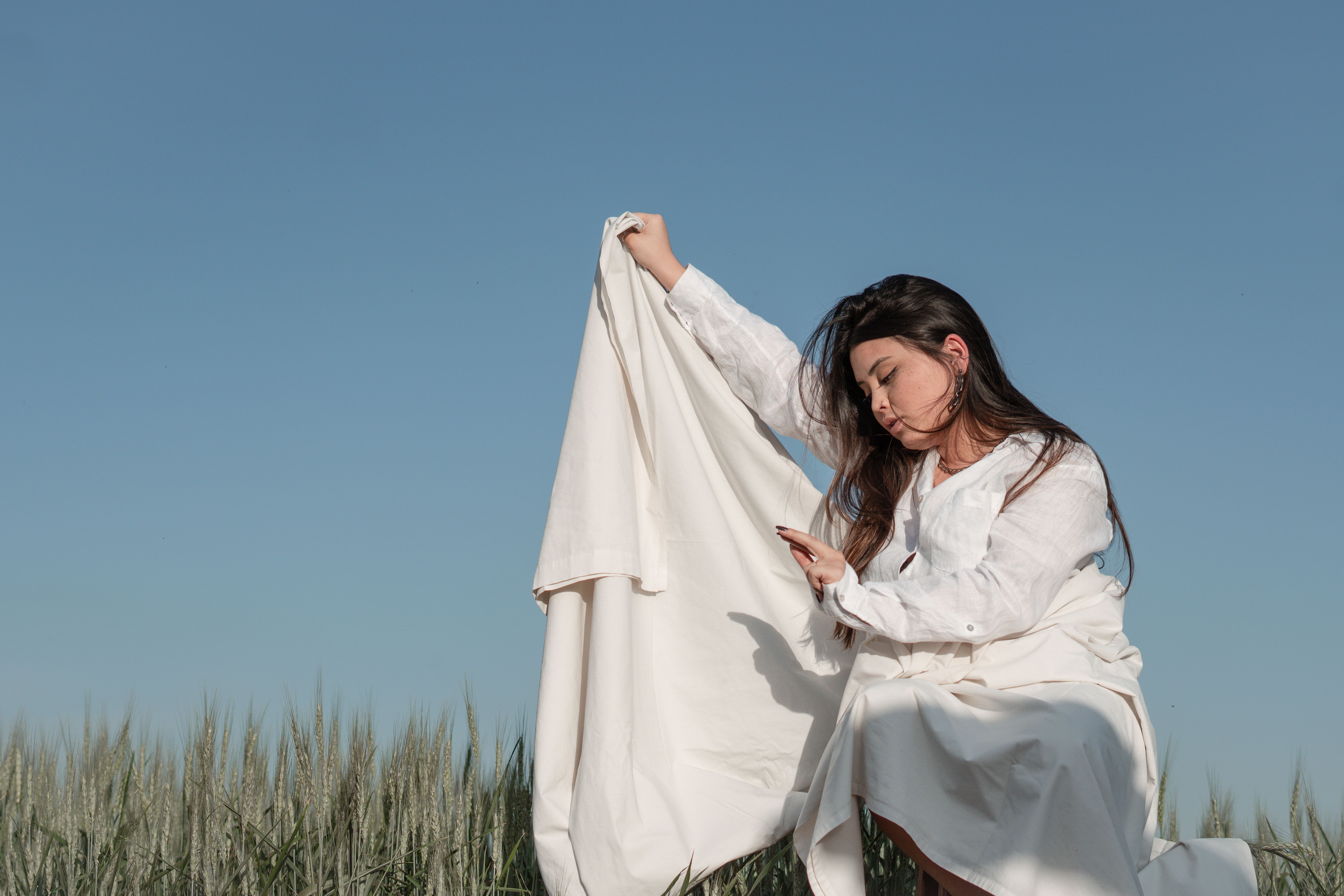 Woman in White Outfit Sitting on Green Grass Field · Free Stock Photo