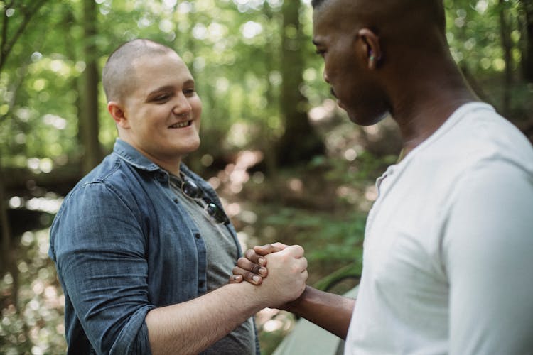 Positive Young Friends Greeting Each Other During Trip In Forest