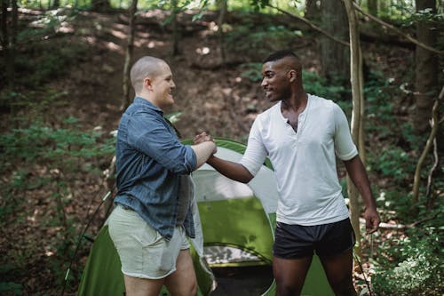 Free Cheerful men resting in forest and shaking hands Stock Photo