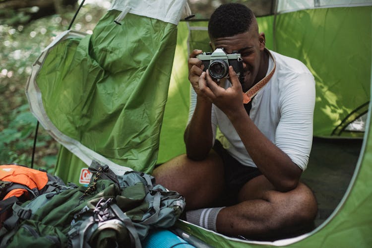 Black Man Taking Photo On Vintage Camera In Nature