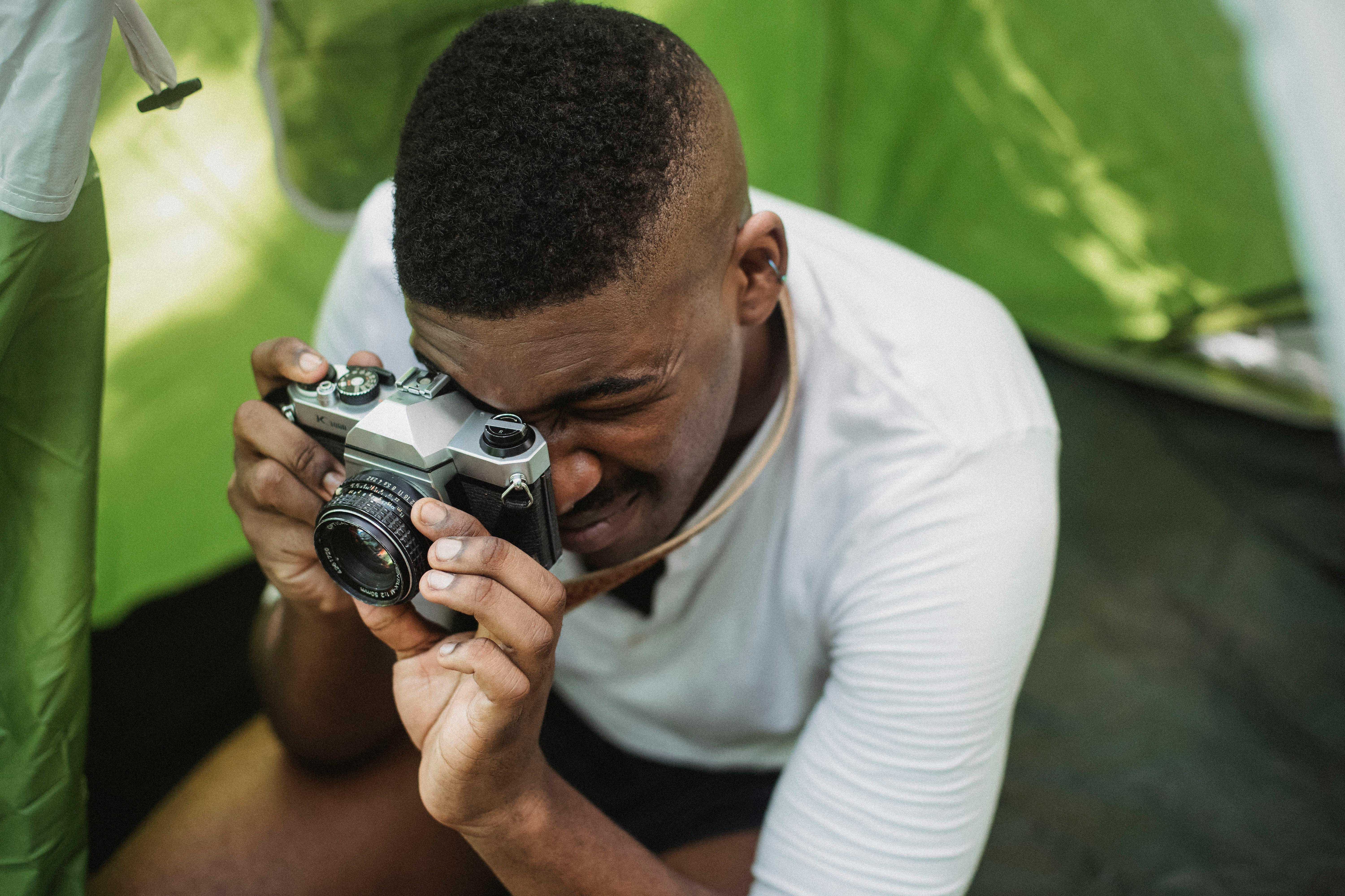 Black male hiker photographing on retro photo camera