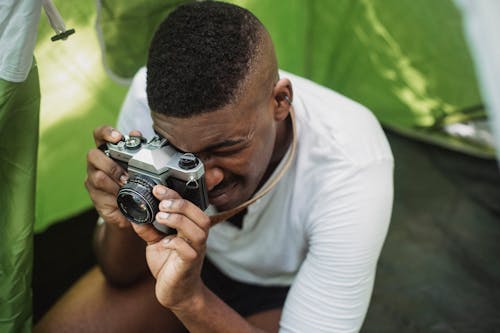 Black male hiker photographing on retro photo camera