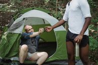 Diverse male hikers with hot beverage in thermos in woods