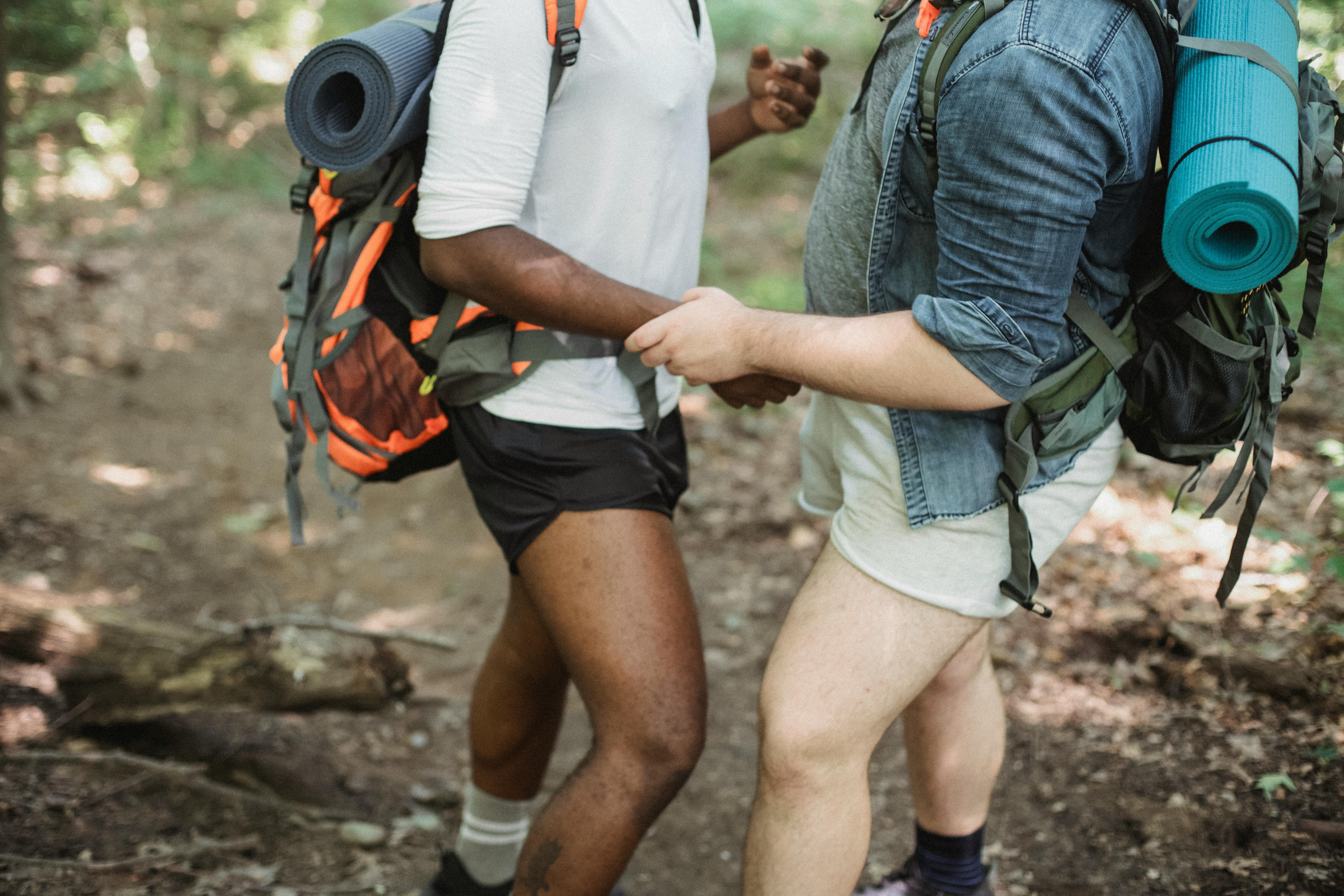 разнообразная гей пара, треккинг в лесу · Бесплатные стоковые фото
