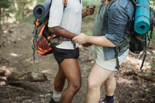 Free Crop unrecognizable multiethnic travelers with backpacks with hiking equipment walking in forest during trekking trip Stock Photo