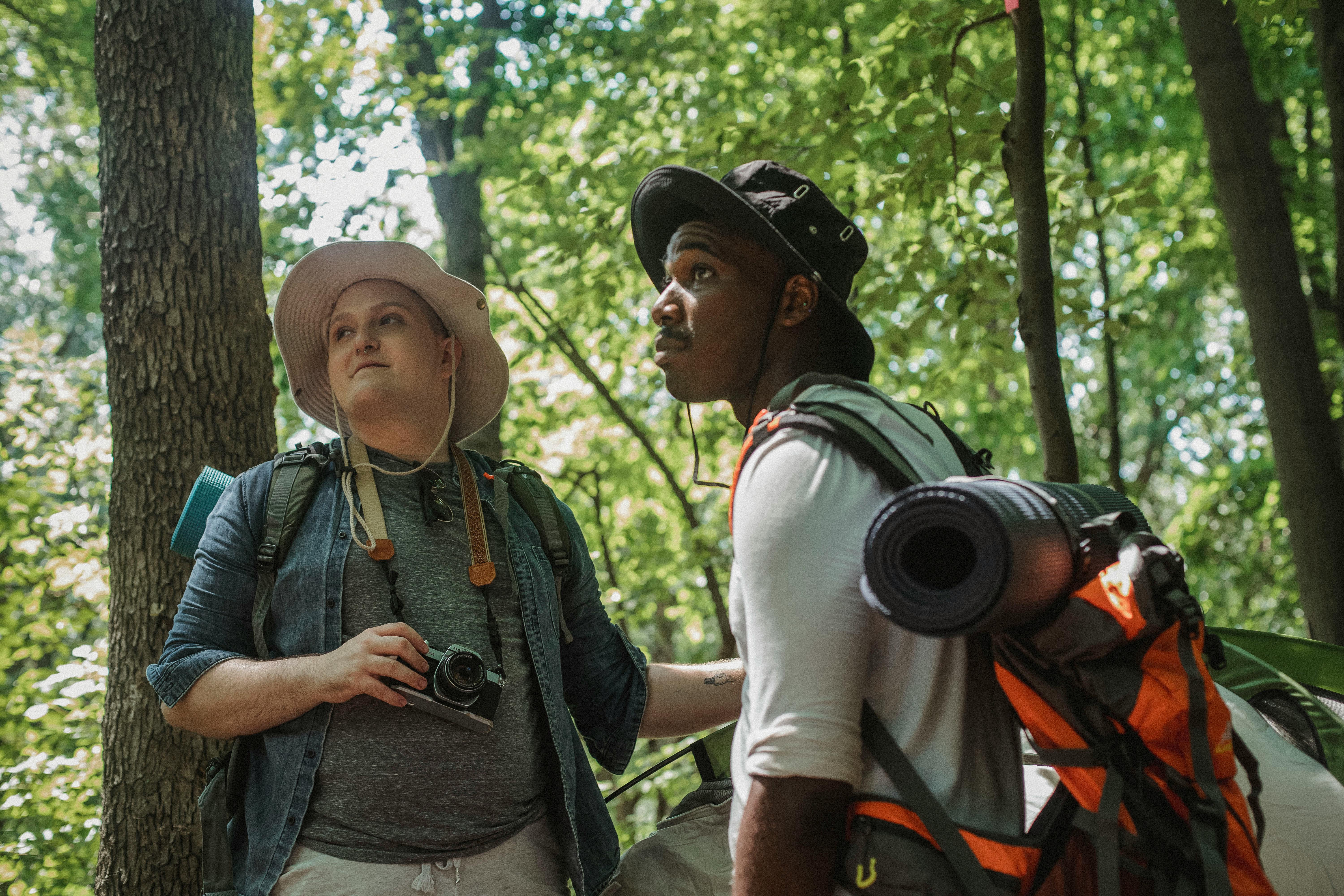 male tourist with retro camera standing next to friend in forest