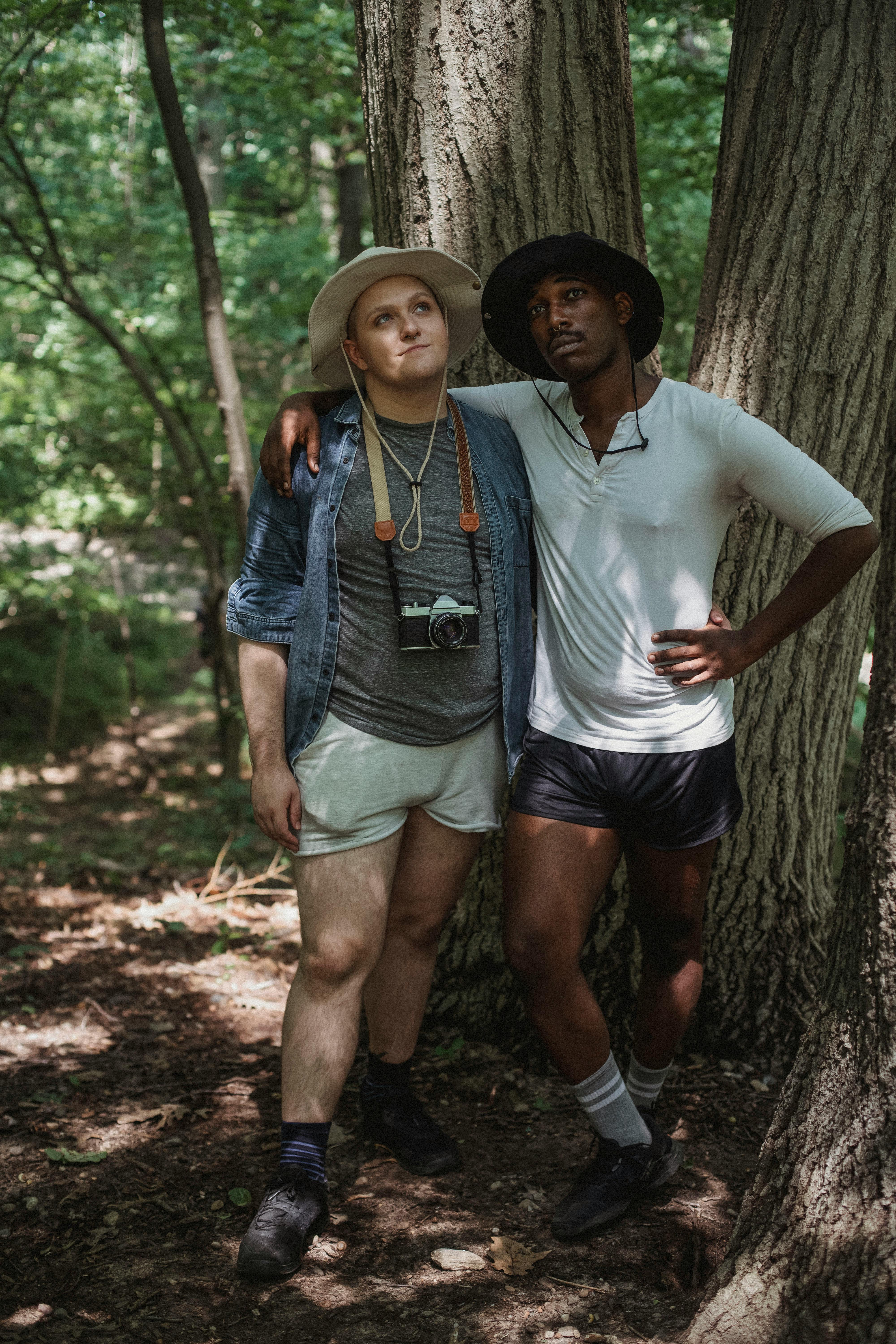 dreamy multiethnic couple of gays embracing in woods