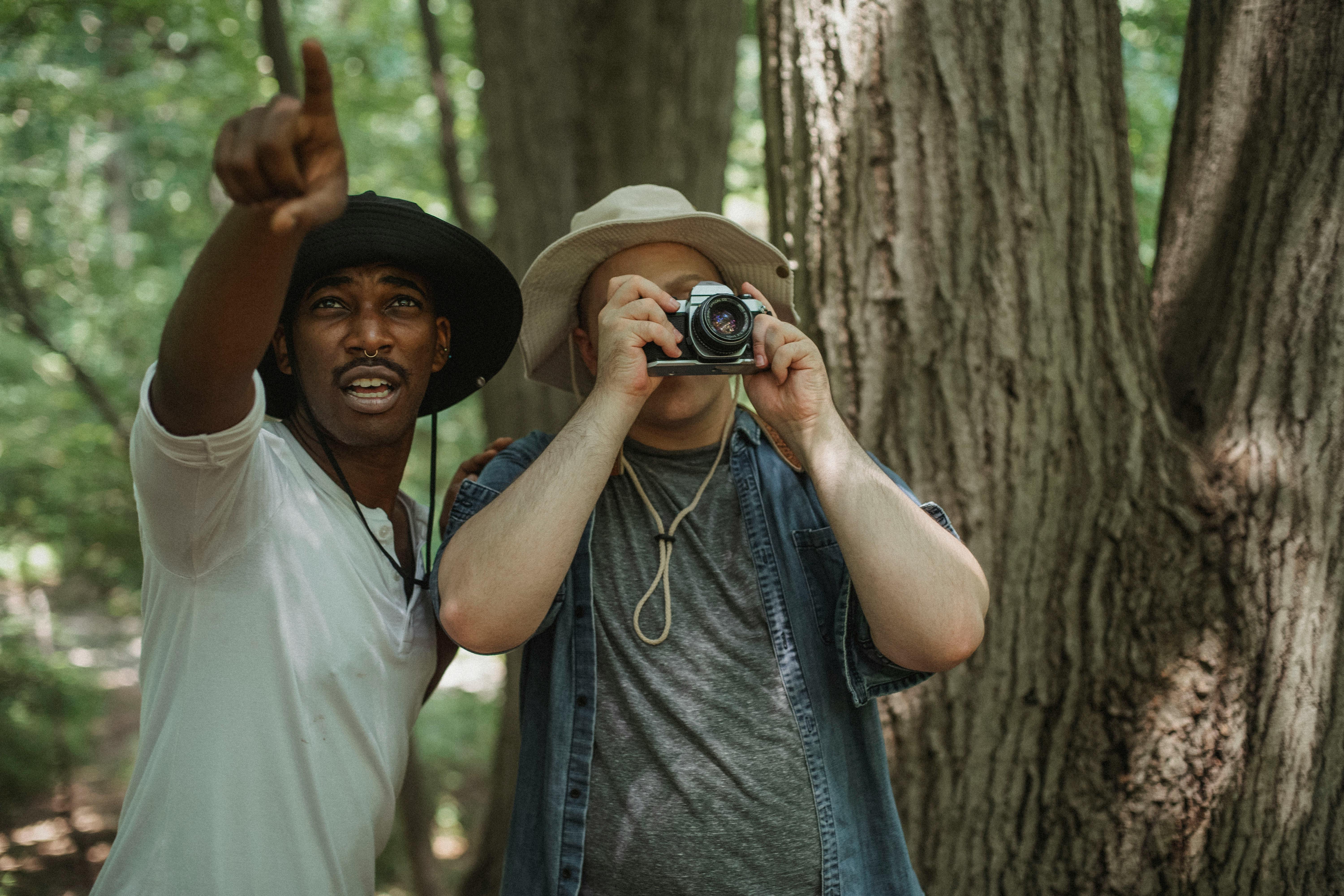 black traveler pointing with finger near friend with photo camera