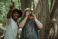 Black traveler pointing with finger near friend with photo camera