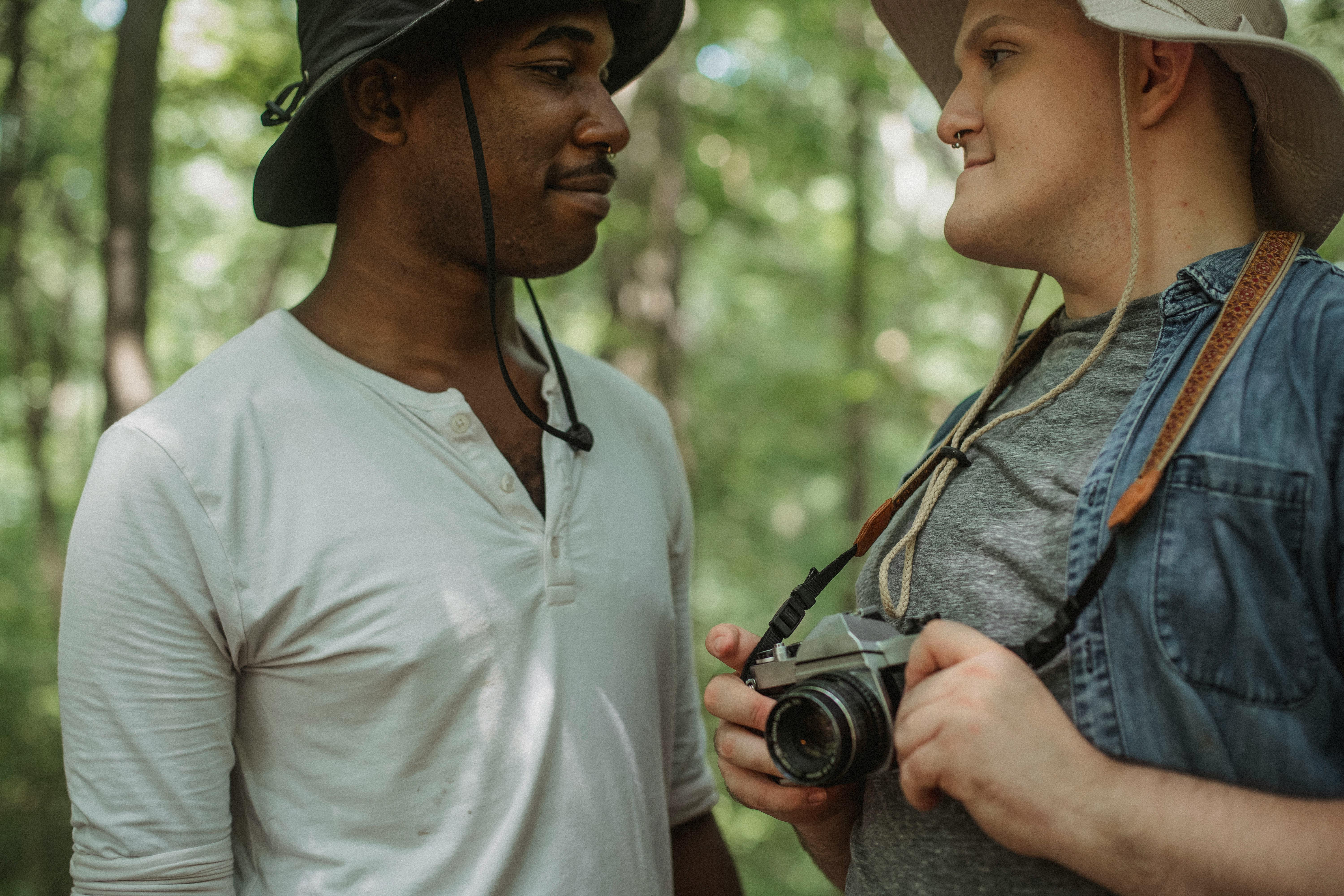 crop multiracial homosexual couple with photo camera in woods