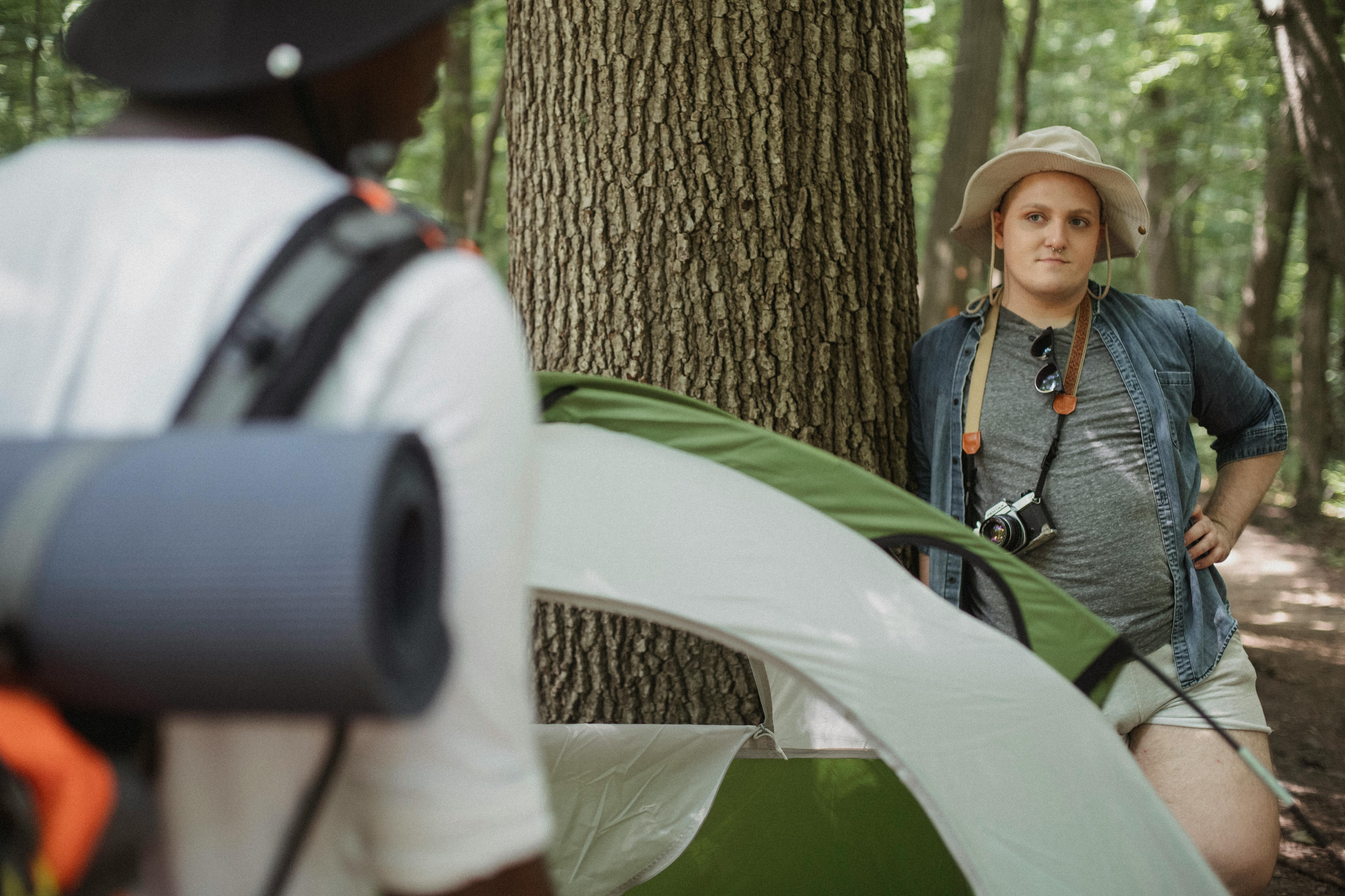 traveler with photo camera near unrecognizable black partner in forest