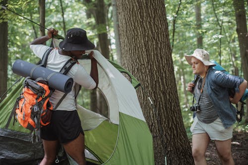 Uomini In Viaggio In Pantaloncini E Cappelli Che Montano Una Tenda Da Campeggio Nei Boschi