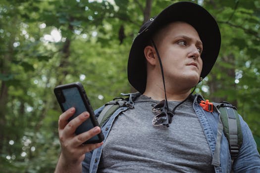 A man with a backpack and smartphone exploring a forest, symbolizing adventure and technology.