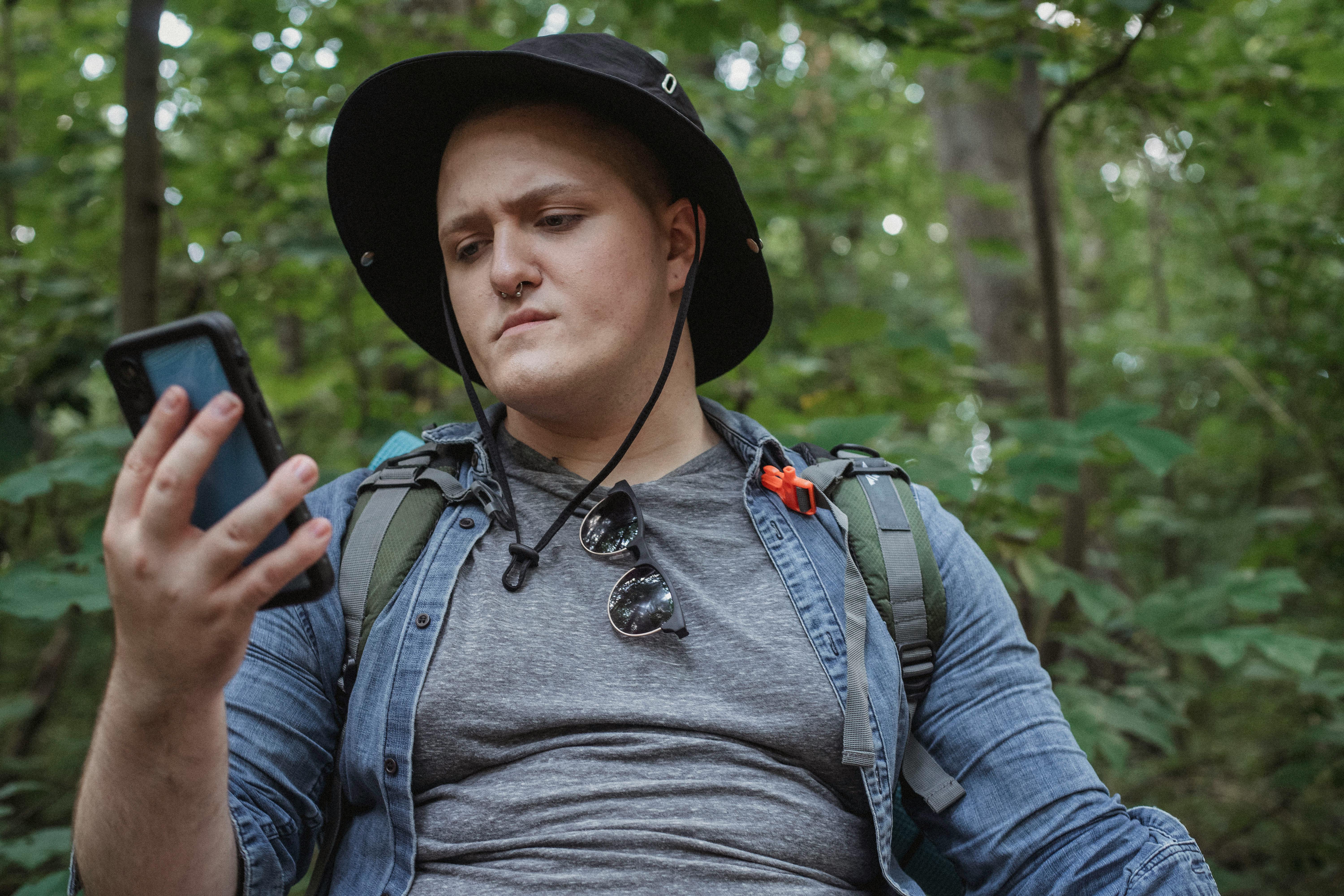 attentive tourist watching smartphone in summer forest