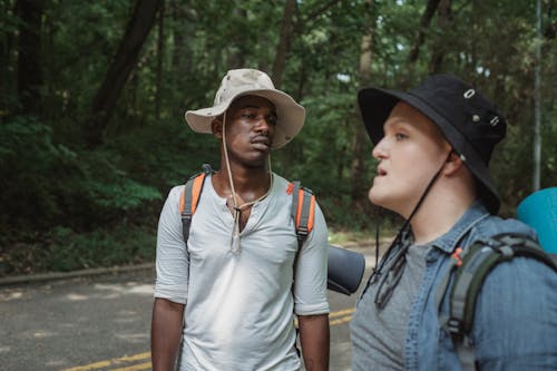 Diverse male travelers with rucksacks conversing on roadway