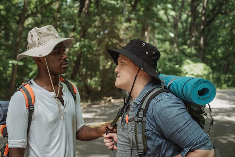 Diverse Male Friends With Hiking Equipment Talking On Road