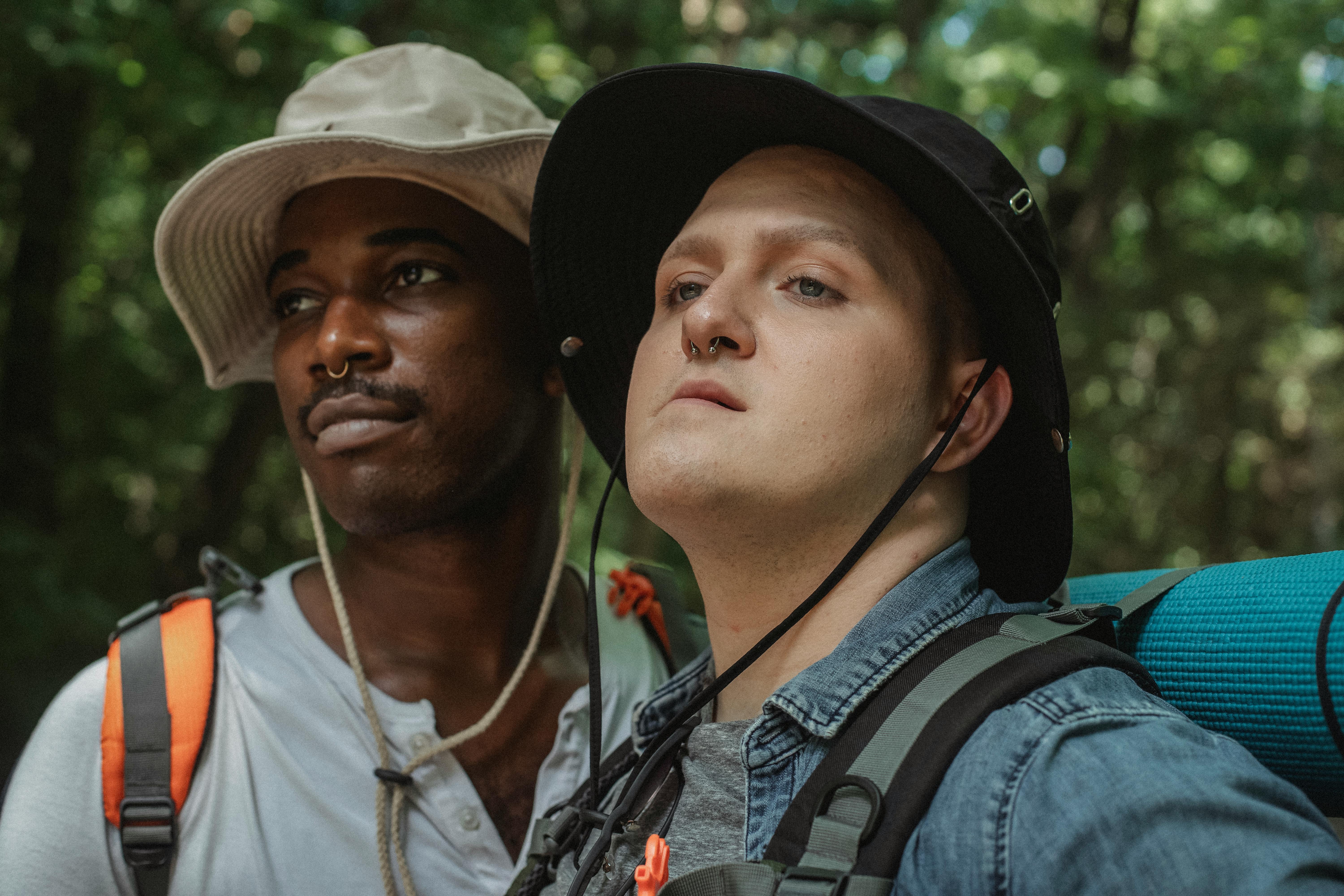 couple of multiracial gays with piercings and backpacks in forest