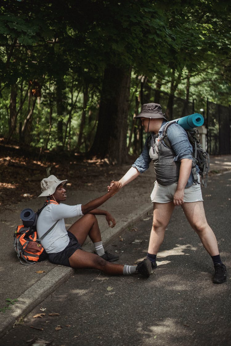 Hiker Holding Hand Of Black Friend On Road