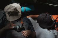 一名穿着休闲服、用帽子遮住脸的男子，在长时间徒步旅行后睡在帐篷里，从上面无法辨认他的样貌
