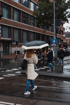 一名妇女打着雨伞，走在阿姆斯特丹潮湿的街道上