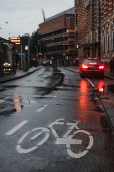 穆迪多雨的街景中，自行车道和黄昏时前灯的反射清晰可见