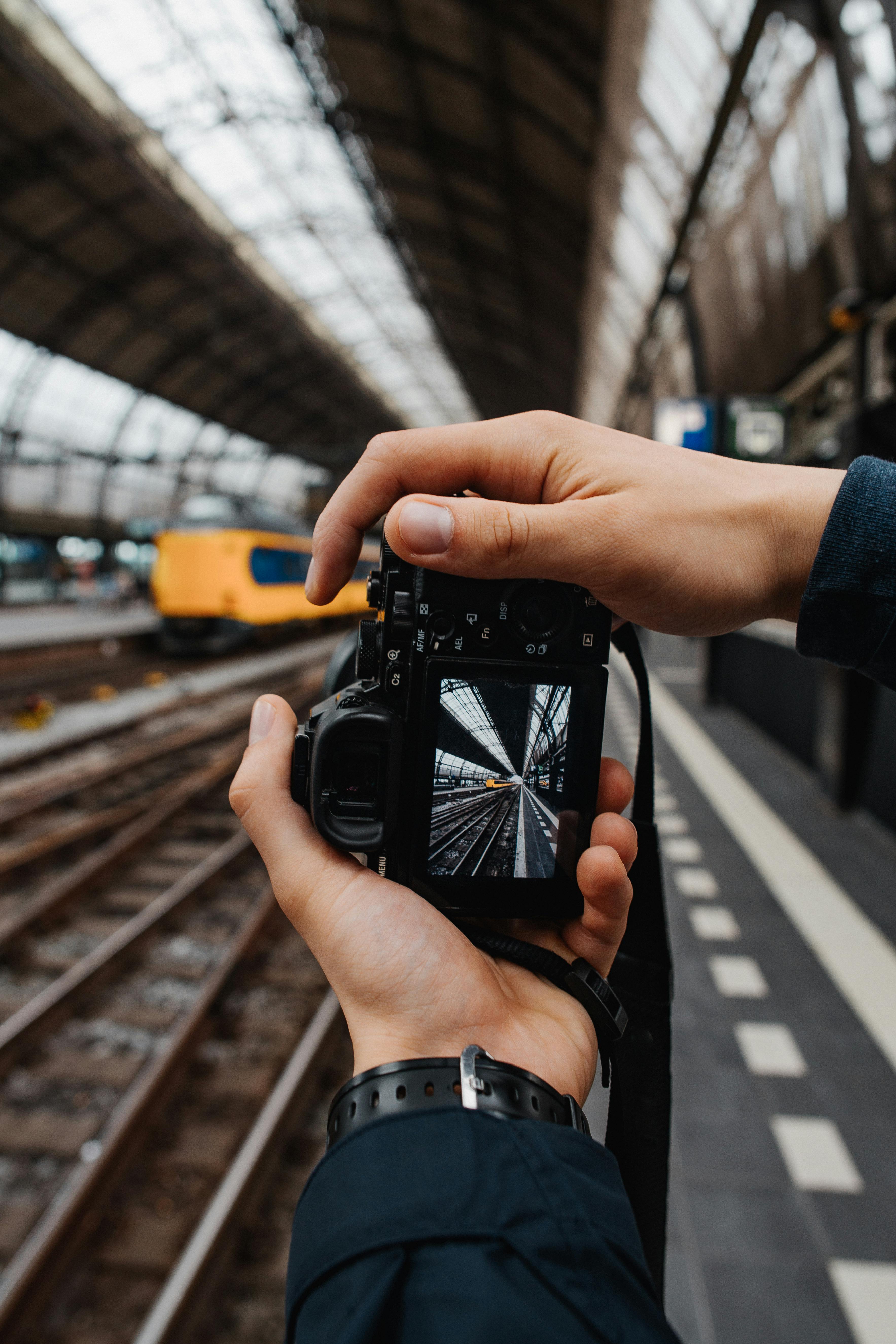 person taking photos of the yellow train using black dslr camera