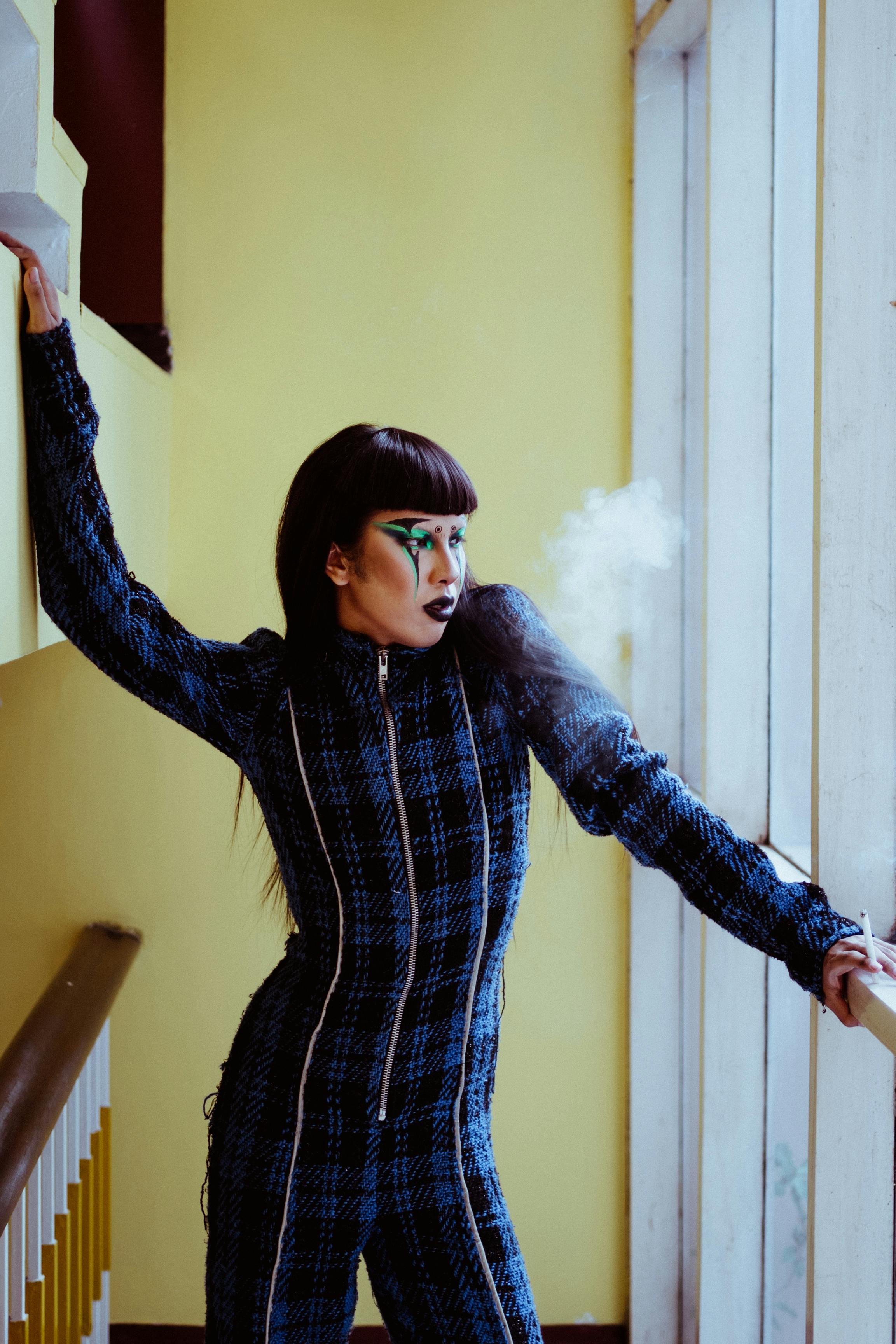 fashionable asian woman with cigarette near window