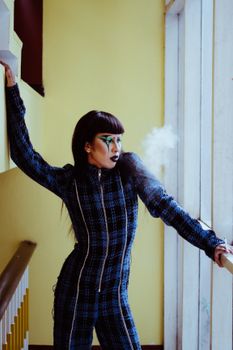 一位妆容艺术的时尚女性在室内吸烟，尽显优雅与个性