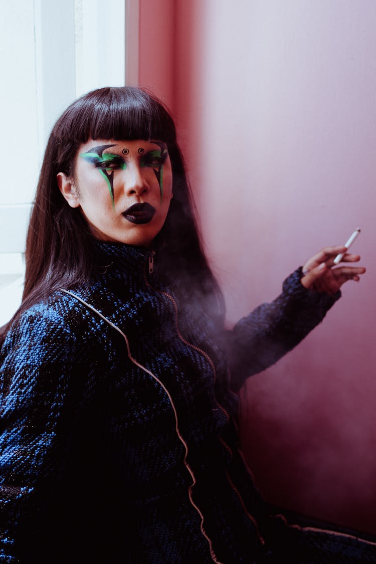 Asian Woman With Bright Makeup Smoking In Room