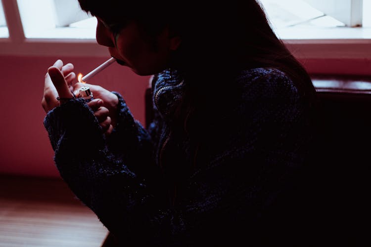 Woman Smoking Cigarette In Dark Room