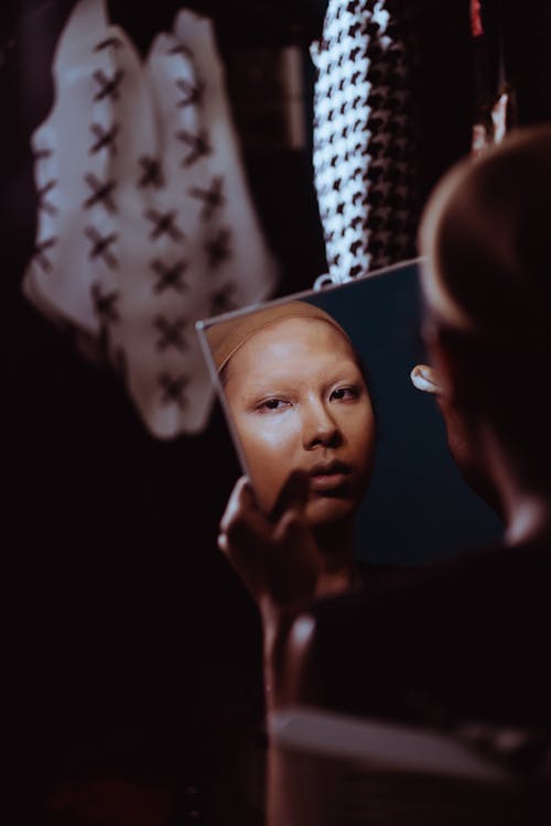 Asian woman with powder on face looking at mirror