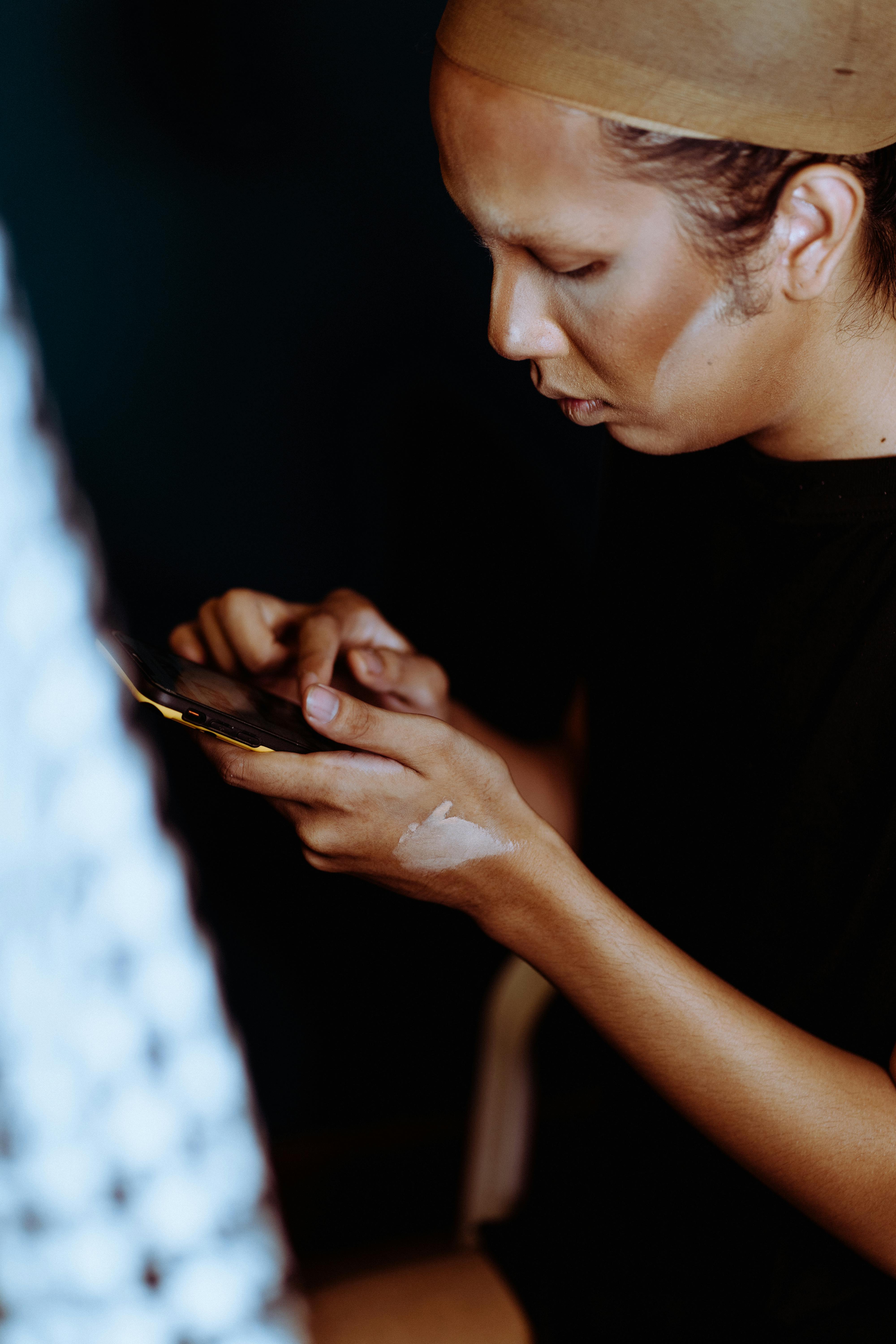 asian woman with foundation on face checking messages in smartphone