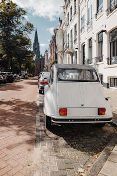 一辆经典的白色汽车停在风景如画的欧洲街道上，背景是历史建筑和教堂