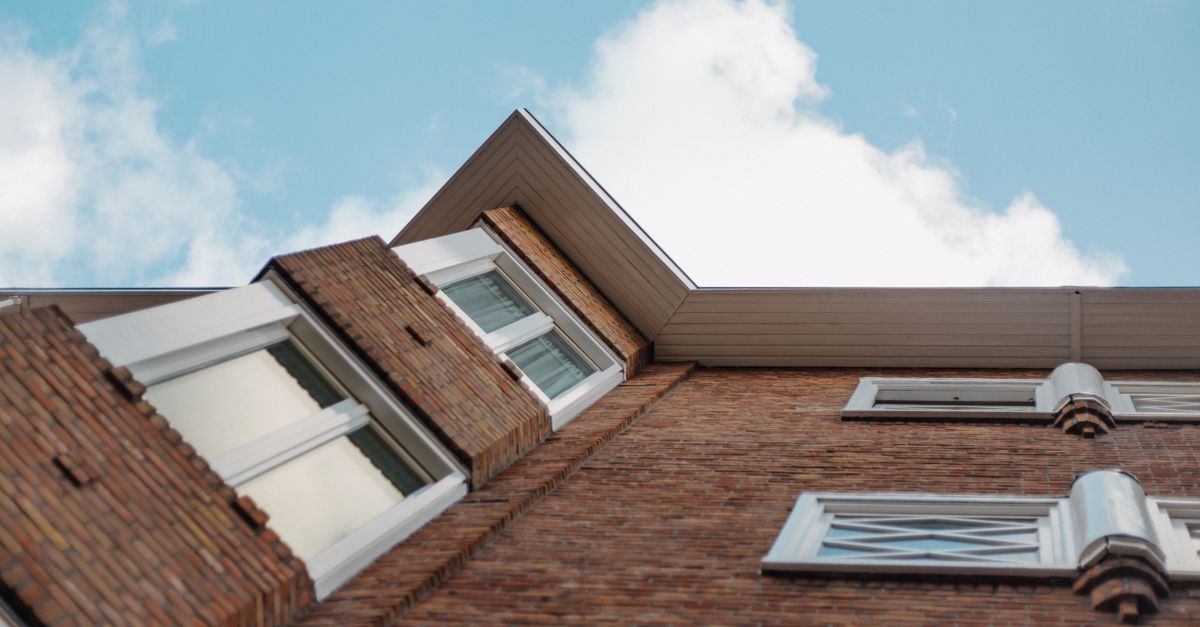 Low angle shot of a brick building with glass windows against a clear blue sky.