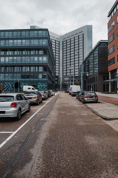 市中心的现代街景中，停放着汽车，矗立着高层建筑