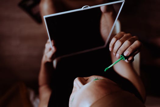 A woman skillfully applies green eyeshadow using a mirror for a modern makeup look.