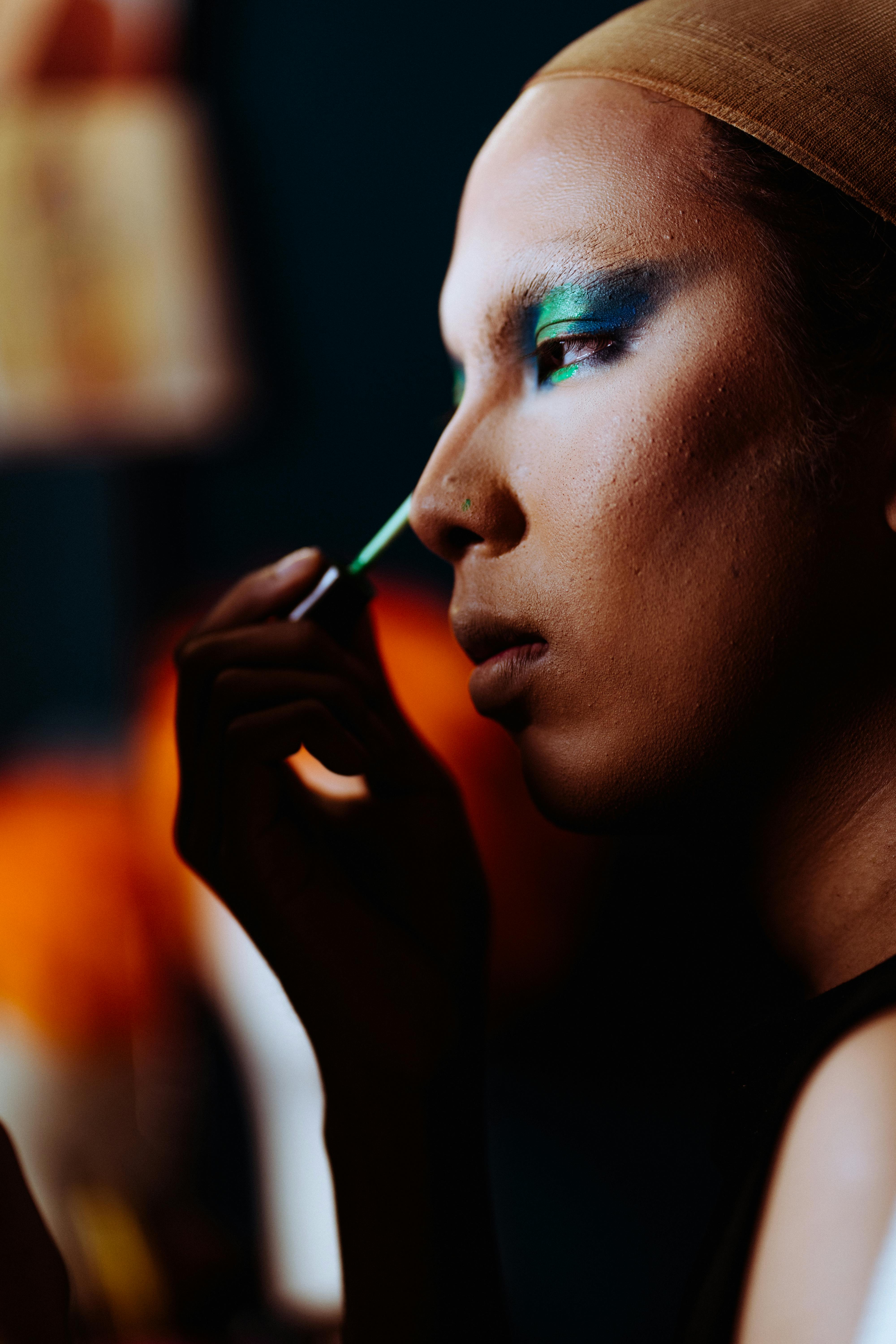 Ethnic woman applying makeup in studio
