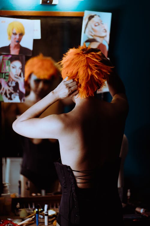 Ethnic transgender man in corset doing hairstyle