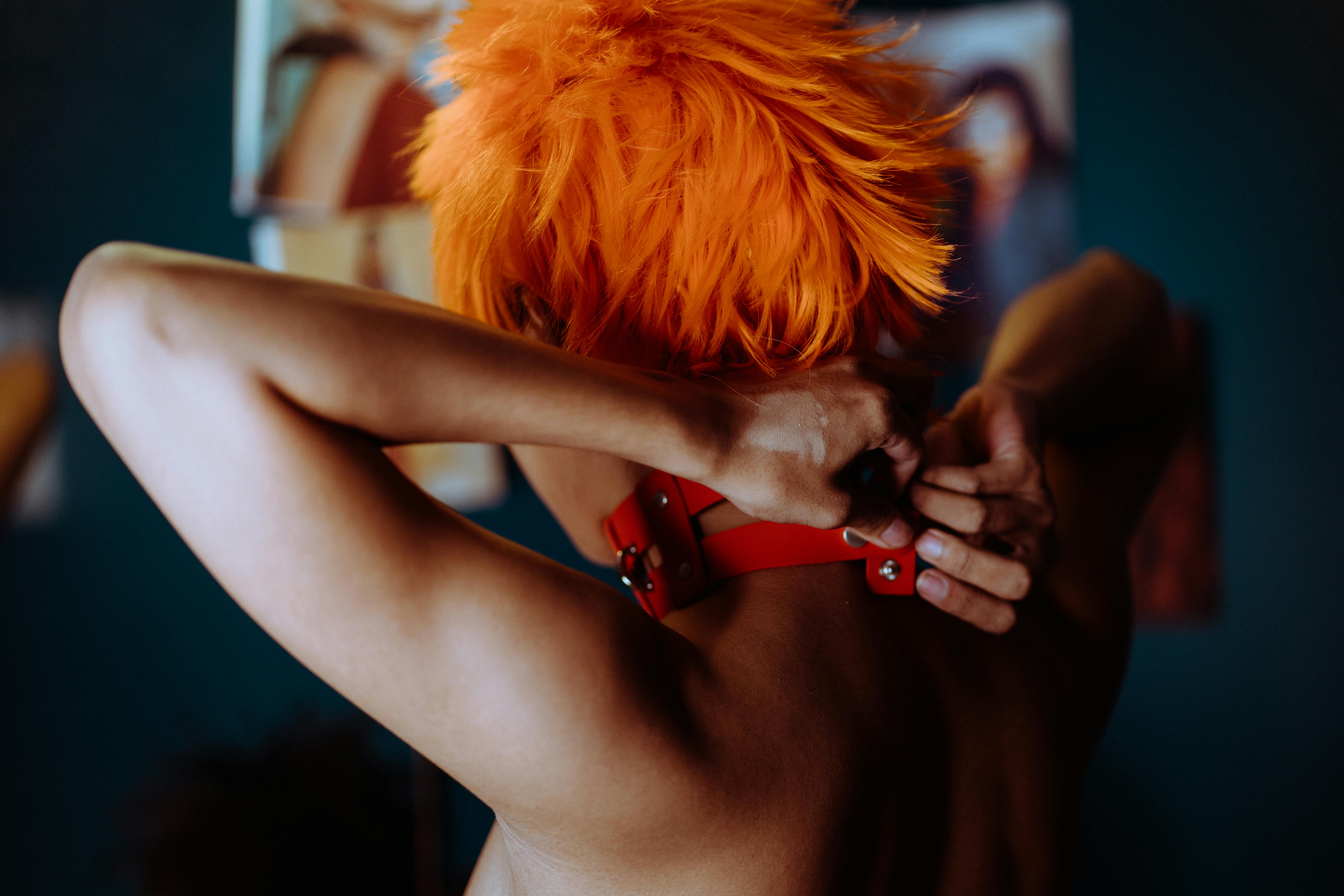 ethnic woman with bright hair putting on choker