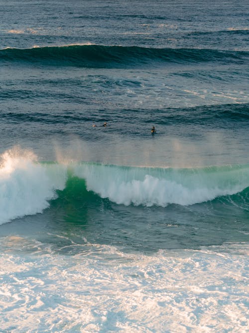 People Surfing on the Big Waves of a Sea