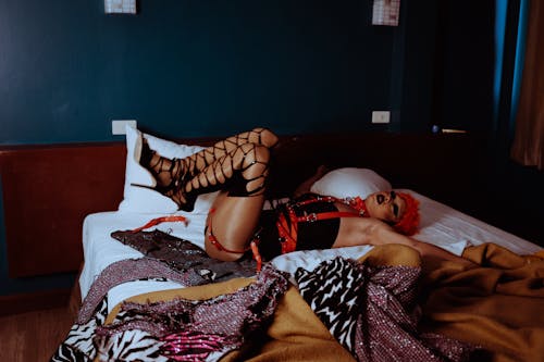 неформальный мужчина трансгендер лежит с поднятыми ногами на кровати