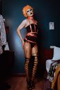 Transsexual man in BDSM outfit standing in dark room