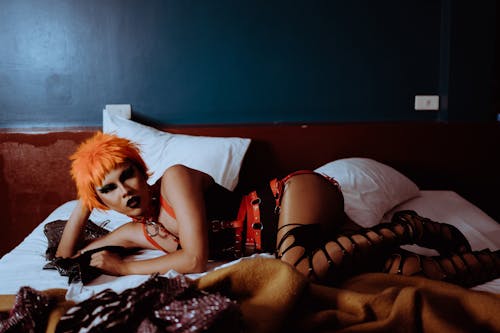 очаровательная этническая транссексуальная проститутка в бдсм аксессуарах лежит на кровати