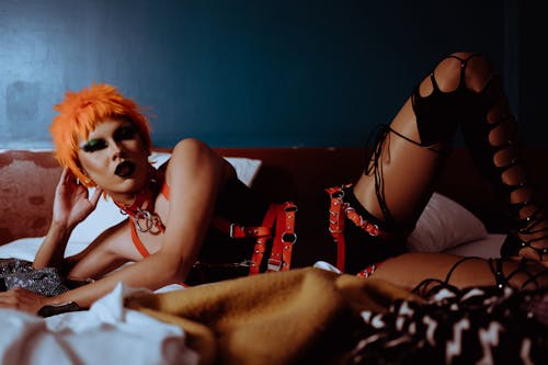 Free Eccentric young ethnic woman in provocative outfit and BDSM accessories lying on bed Stock Photo